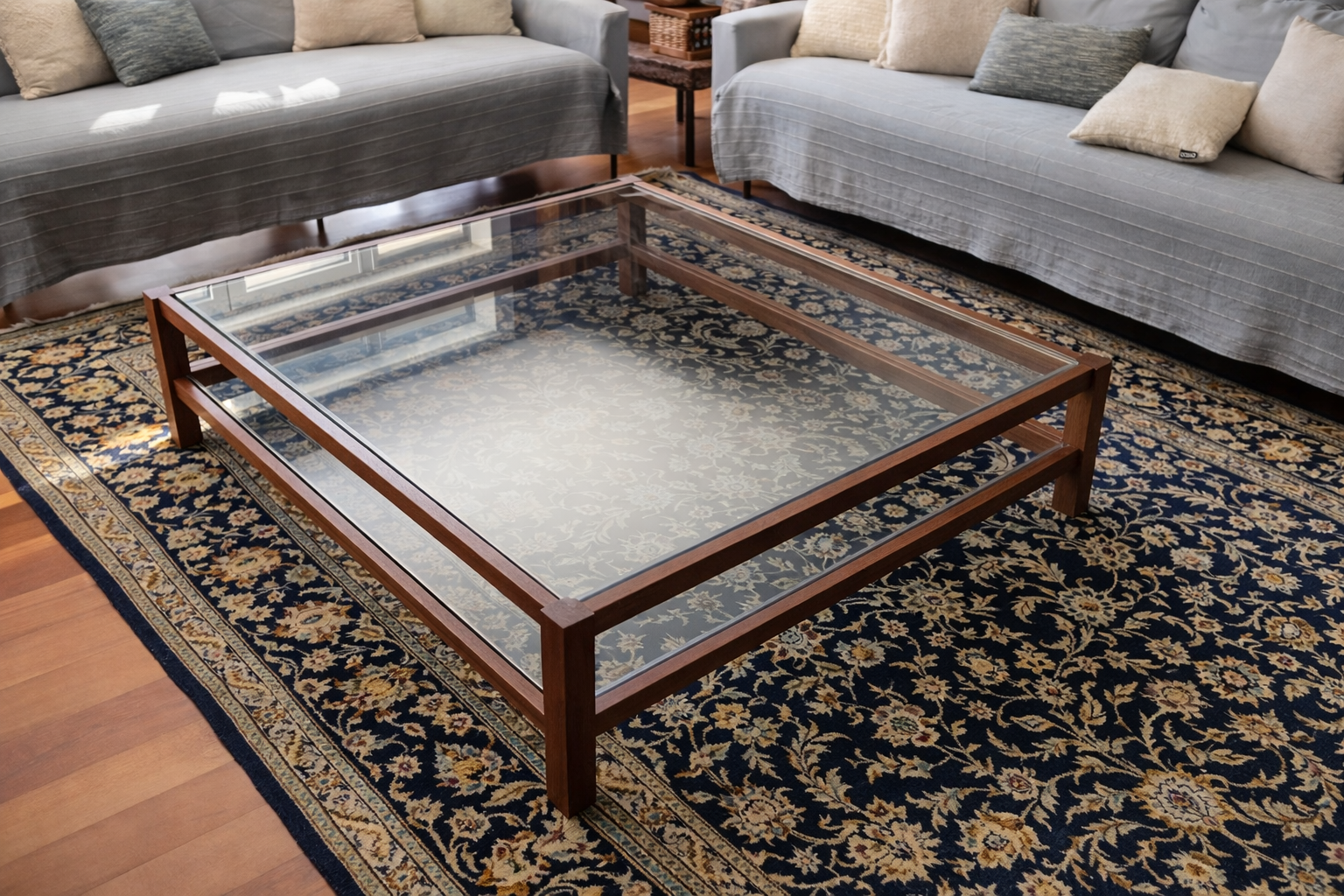 Walnut-framed glass coffee table on a patterned rug in a living room